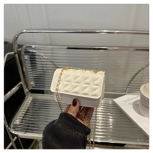 Detailed view of white quilted mini chain bag with glossy finish and gold strap