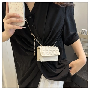 Close-up of white quilted mini crossbody bag with gold chain strap worn by a model