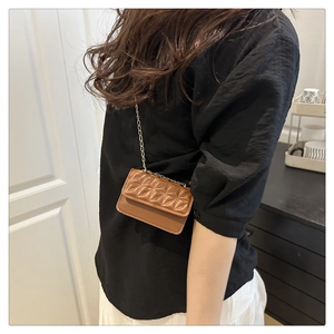 Brown mini crossbody bag with star-shaped quilting and a fine metal chain strap