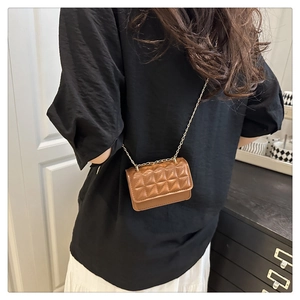 Brown mini crossbody bag with quilted rhombic pattern and gold chain strap on model