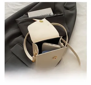 Vue intérieure montrant la capacité d'un sac bandoulière en cuir beige avec un téléphone