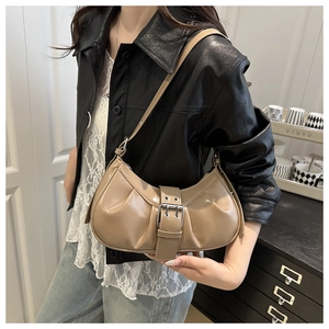 Close-up of light brown pleated crescent bag featuring a glossy finish and metal buckle