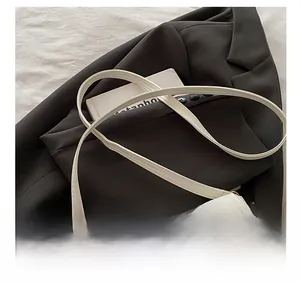 Detail view of the white leather crossbody bag with adjustable strap and gold metal buckle