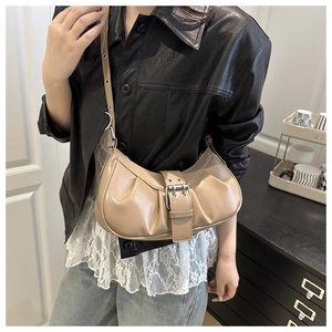 Side view of beige pleated crescent bag with silver metallic buckle on black leather jacket