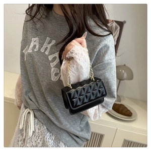Close-up of black quilted crossbody bag with luxury gold chain strap and texture