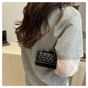 Detail of classic black quilted leather bag with elegant gold chain shoulder strap