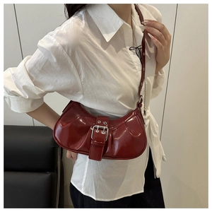 Macro detail of wine red crescent bag with glossy pleated finish and silver buckle