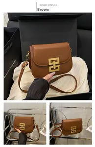 Close-up of brown leather bag with geometric gold buckle and textured leather detail