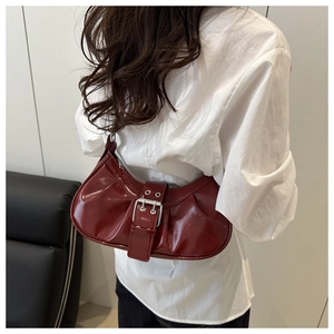 Detail view of burgundy crescent bag featuring pleated glossy leather and silver hardware