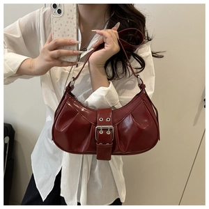 Detail of burgundy glossy patent leather crescent bag with silver buckle and pleats