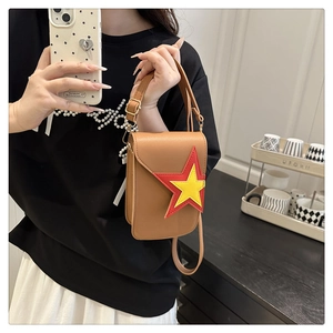 Petit sac à bandoulière en cuir marron avec étoile jaune porté par un modèle dans le miroir