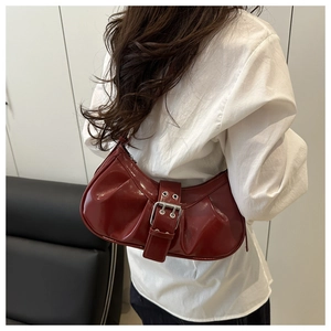 Detail of burgundy vintage pleated shoulder bag featuring silver buckle and glossy finish