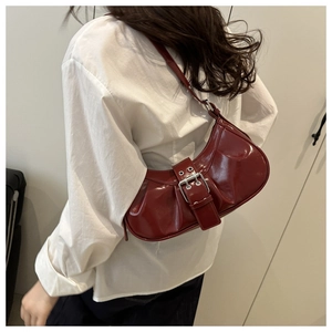 Detailed side view of wine red pleated crescent bag with metal buckle and glossy leather