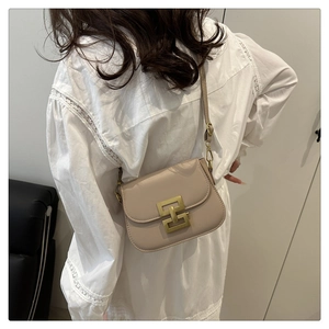 Detail of minimalist beige crossbody bag with gold buckle on a model in white lace top