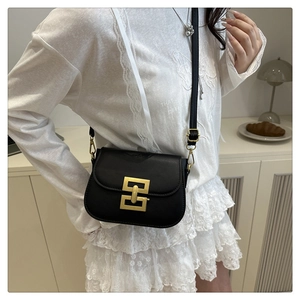 Detail of a vintage black leather square bag with a luxury gold geometric buckle and strap