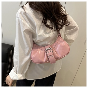Detail of pink patent leather crescent bag with metal buckle and grommets on white shirt