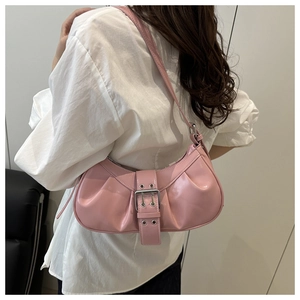 Detail of pink patent leather crescent hobo bag with metallic buckles and eyelets