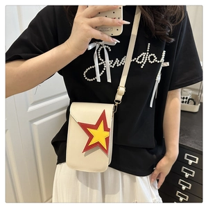 Détail d'un sac à bandoulière crème avec étoiles colorées porté par un modèle