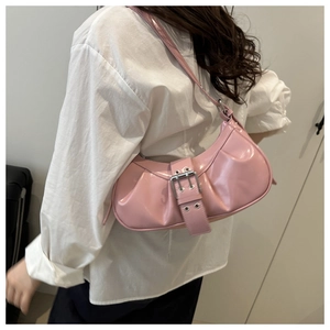 Pink glossy patent leather crescent bag with pleated details and silver buckle on model
