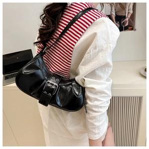 Detail of black glossy shoulder bag with pleated leather texture and metal buckle