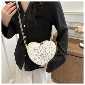 Close-up of heart-shaped crossbody bag with spider web pattern on a female model