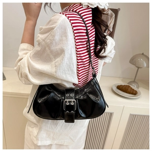 Detail of black glossy patent leather shoulder bag with silver buckle and pleated texture