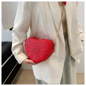 Close-up of red heart-shaped crossbody bag with black spider web embroidery and gold chain