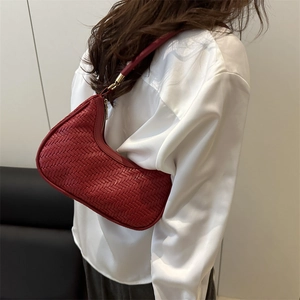 Deep red woven crescent hobo bag with gold zipper detail, shown styled by model