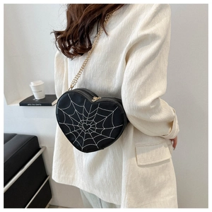 Detailed embroidery of white spider web on a heart-shaped gothic shoulder bag