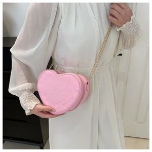 Pink heart-shaped crossbody bag with white spider web embroidery and gold chain strap