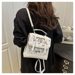 Detailed back view of a white lace backpack with heart pendant on a model in a room