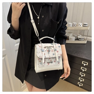 Close-up of white leather handbag with floral embroidery lace and heart charm