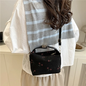 Sweet cherry pattern crossbody bag in black fabric shown on model with soft lighting