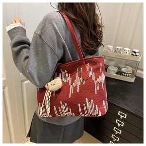 Detail der roten Jacquard-Tasche mit abstrakten Linien und süßem Bären-Anhänger