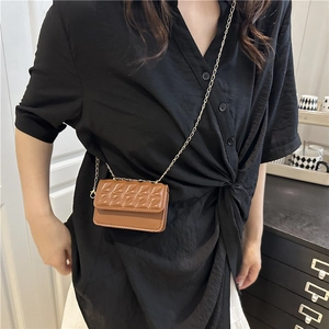 Brown mini crossbody bag with diamond quilting and gold chain on a black outfit