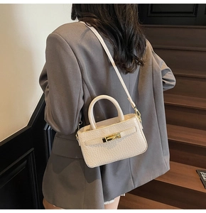 Detail of white crocodile pattern handbag featuring a gold lock and fine leather texture