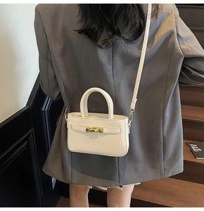 Detail of cream crocodile embossed handbag with gold lock on shoulder model