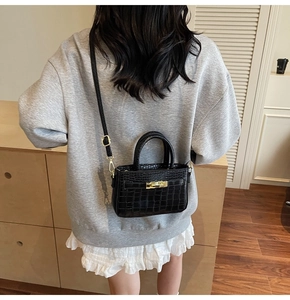 Black crocodile embossed mini crossbody bag with gold hardware shown on a model