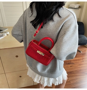 Detail of red crocodile embossed crossbody bag with gold buckle on casual outfit