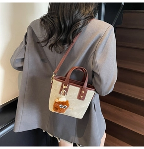 Detail of canvas bucket bag with leather trim and plush monster charm on a staircase