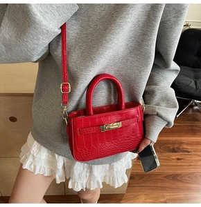 Detail of red crocodile texture bag with gold twist lock and elegant top handle