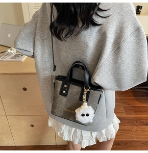 Detail view of a vintage grey mini tote bag with a white plush monster charm on the strap