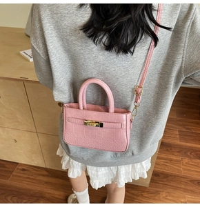 Rear view of a pink crocodile-embossed handbag with gold hardware and a long shoulder strap