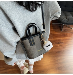 Close-up of mini tote bag in grey faux suede with leather handles and monster charm