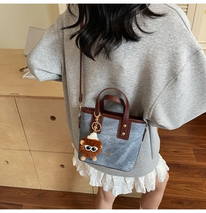 Blue denim bucket bag with brown leather trim and a cute plush monster pendant detail