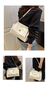 Close-up of white flap shoulder bag featuring gold square buckle and metal chain strap