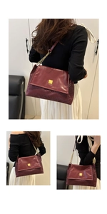 Close-up of burgundy shoulder bag featuring snake skin texture and gold chain strap
