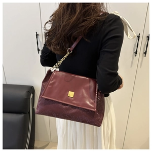 Détail du sac bandoulière bordeaux avec motif serpent et boucle dorée sur modèle
