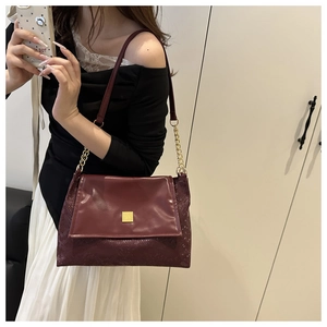 Détail du sac bandoulière bordeaux avec boucles dorées et texture serpent sur les côtés