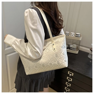 Close-up of white embossed tote bag featuring textured geometric and floral jacquard patterns